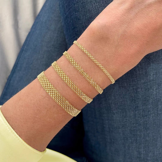 Woman wearing multiple 14K gold mesh chain bracelets stacked on wrist showing certified authentic luxury jewelry everyday styling NYC